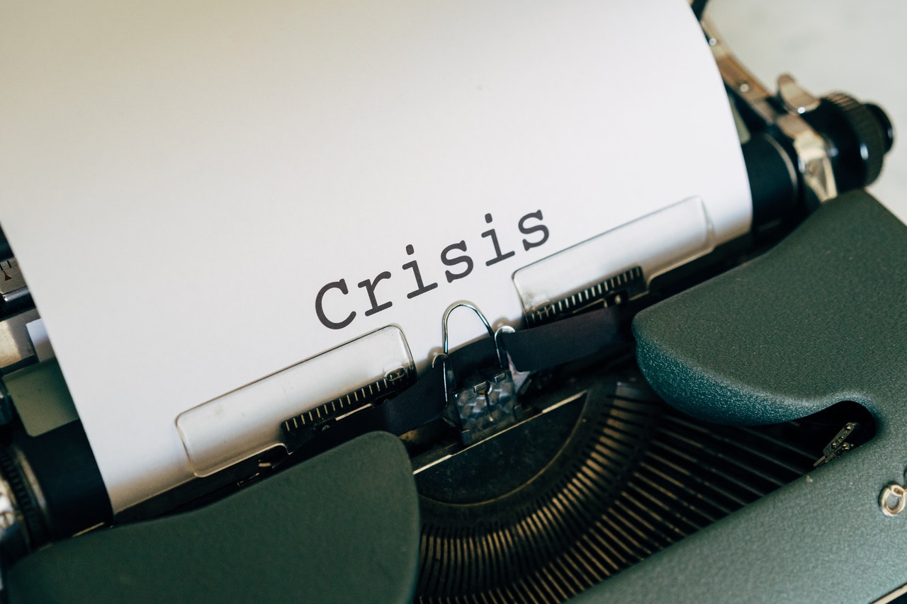 A typewriter and a paper with crisis written on it