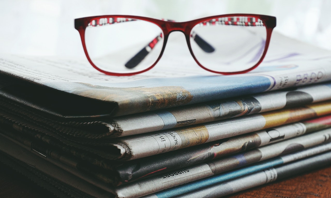 A pair of glasses on some news/ report papers