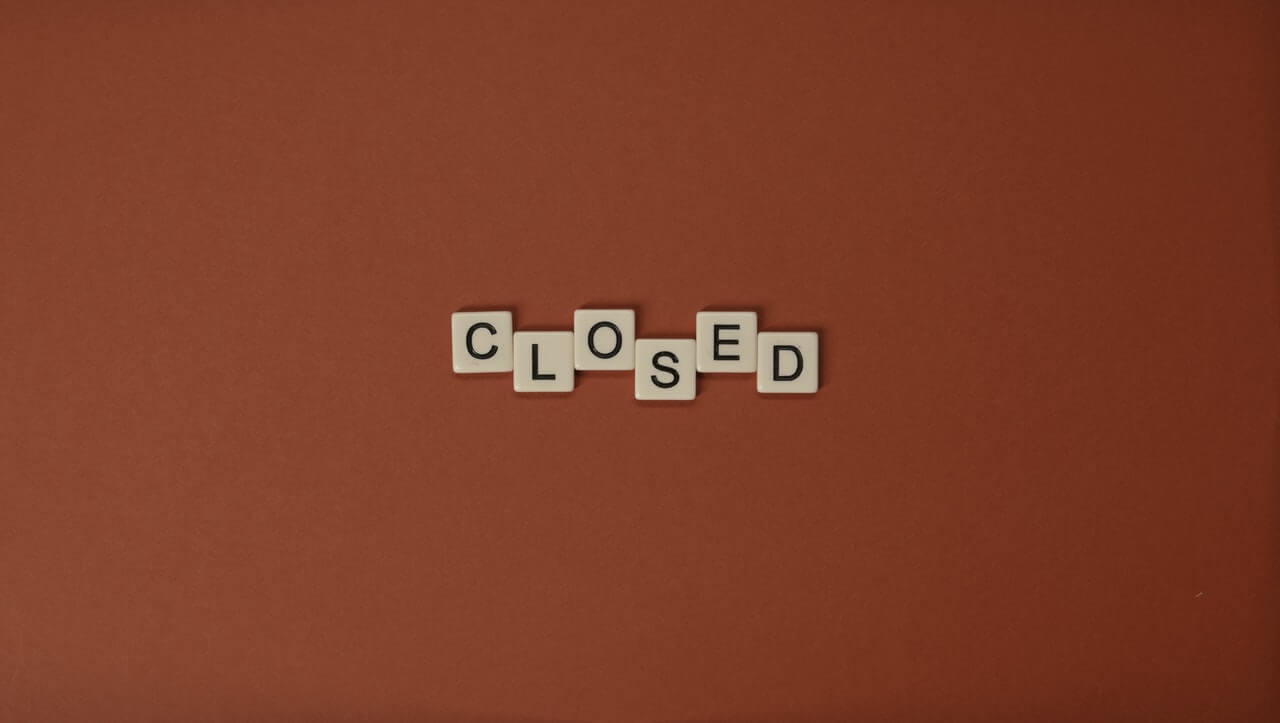 Wooden tiles arranged to spell "closed" on a plain background