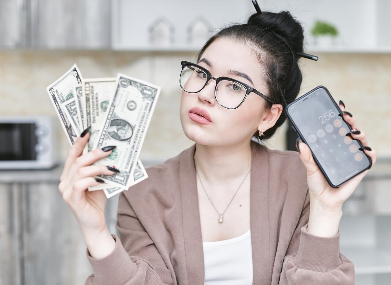 Corporate woman holding dollar bills and a smartphone