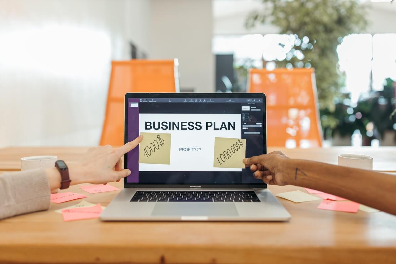 Hand pointing to a business plan on a laptop