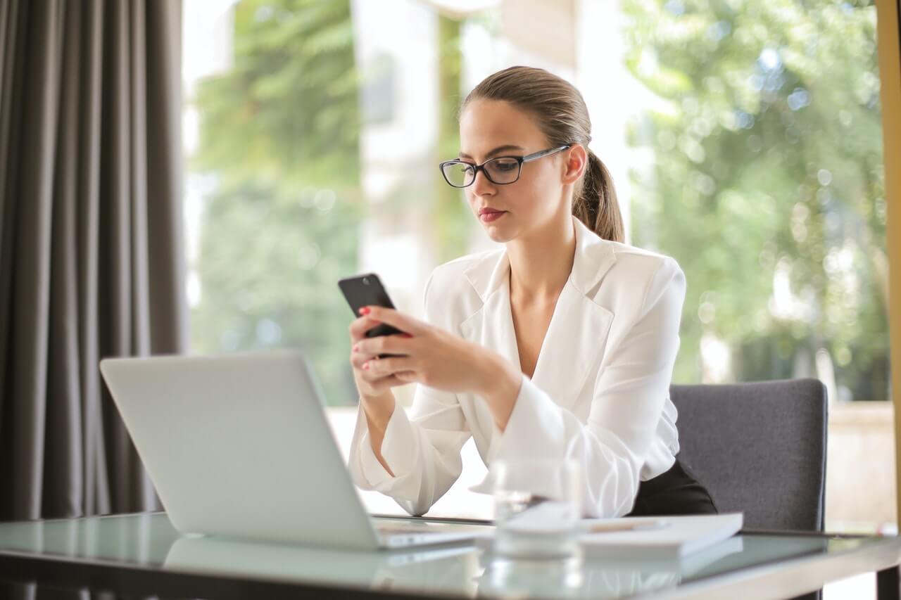 Businesswoman using her phone while at her office desk