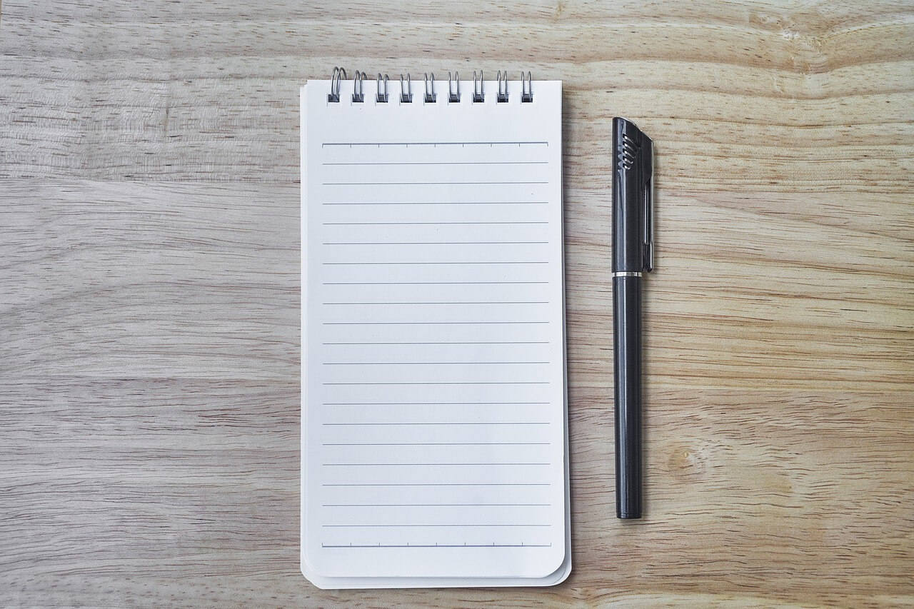 A notebook and pen on a grey background