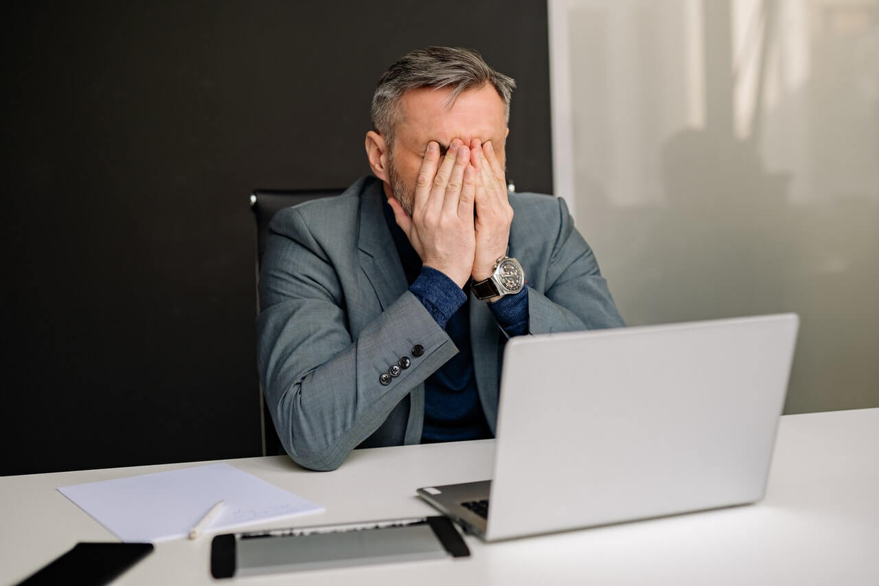 A worried businessman with a laptop in an office