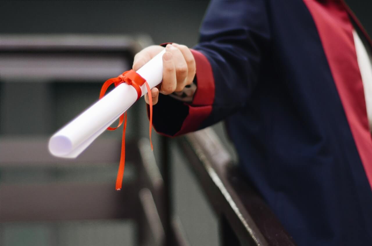 Person holding a certificate with a red ribbon