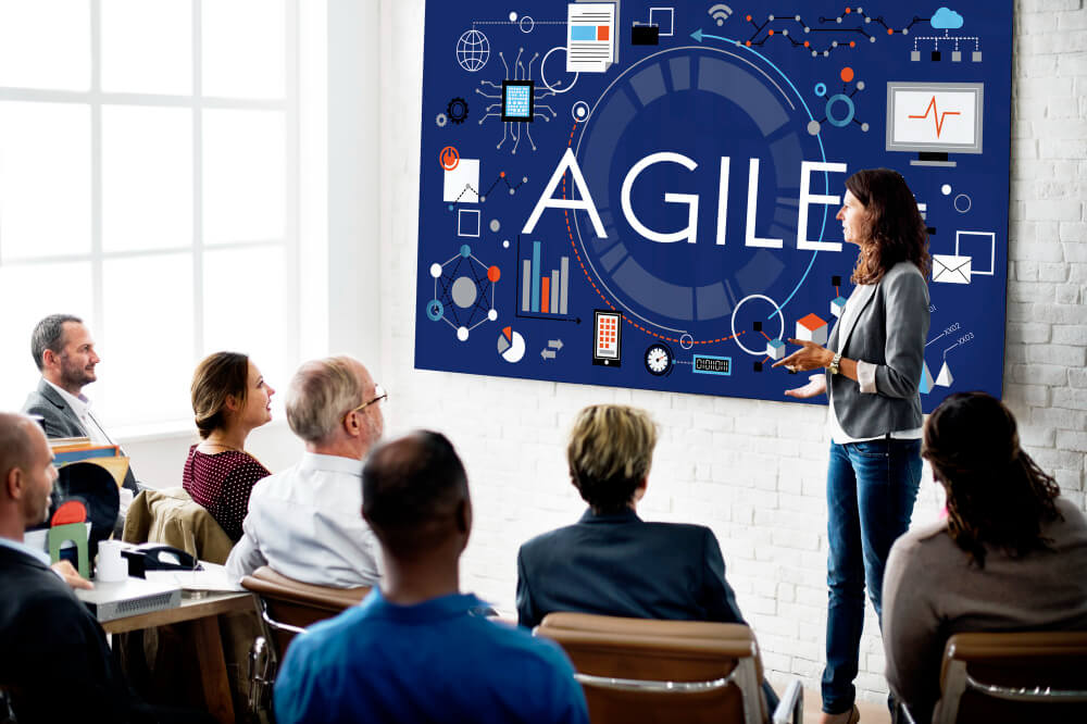 A corporate woman giving a presentation on agile methodology to a group of persons