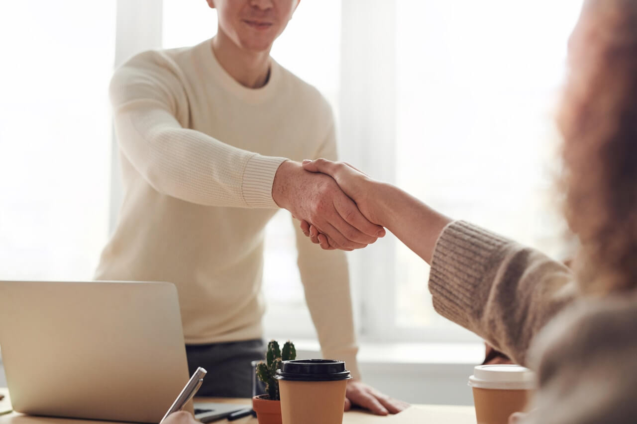Two people shaking hands on an agreement in an office