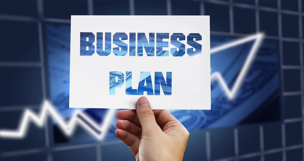 hand holding a note that says "business plan" against a corporate background