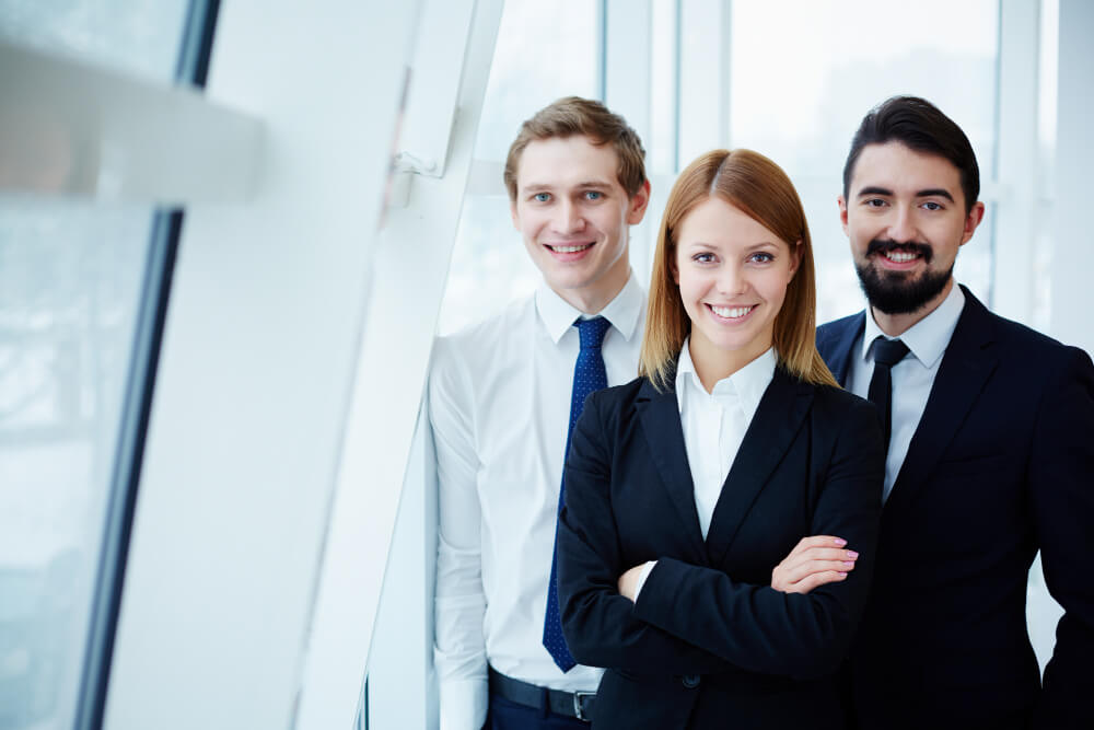Smiling corporate workers standing beside a window