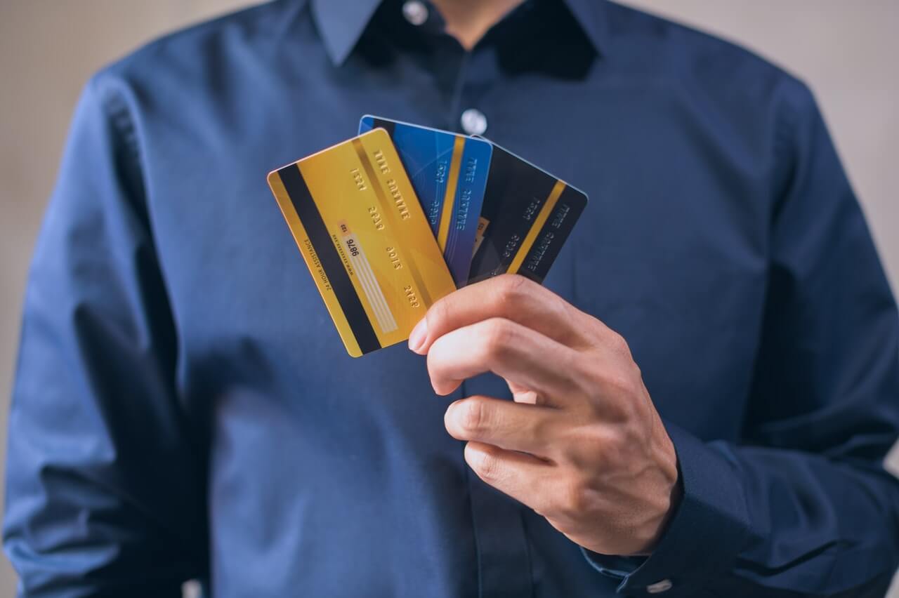 Man with head cropped off holding the different best prepaid debit cards