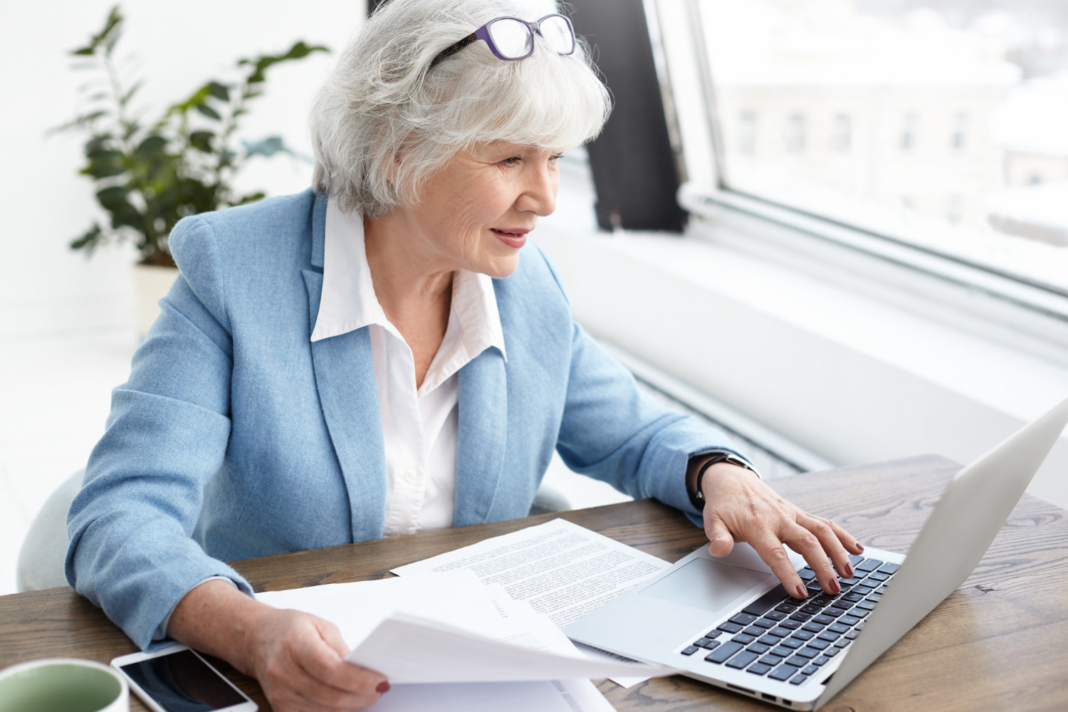 An-elderly-female-executive-compiling-documents-with-her-laptop