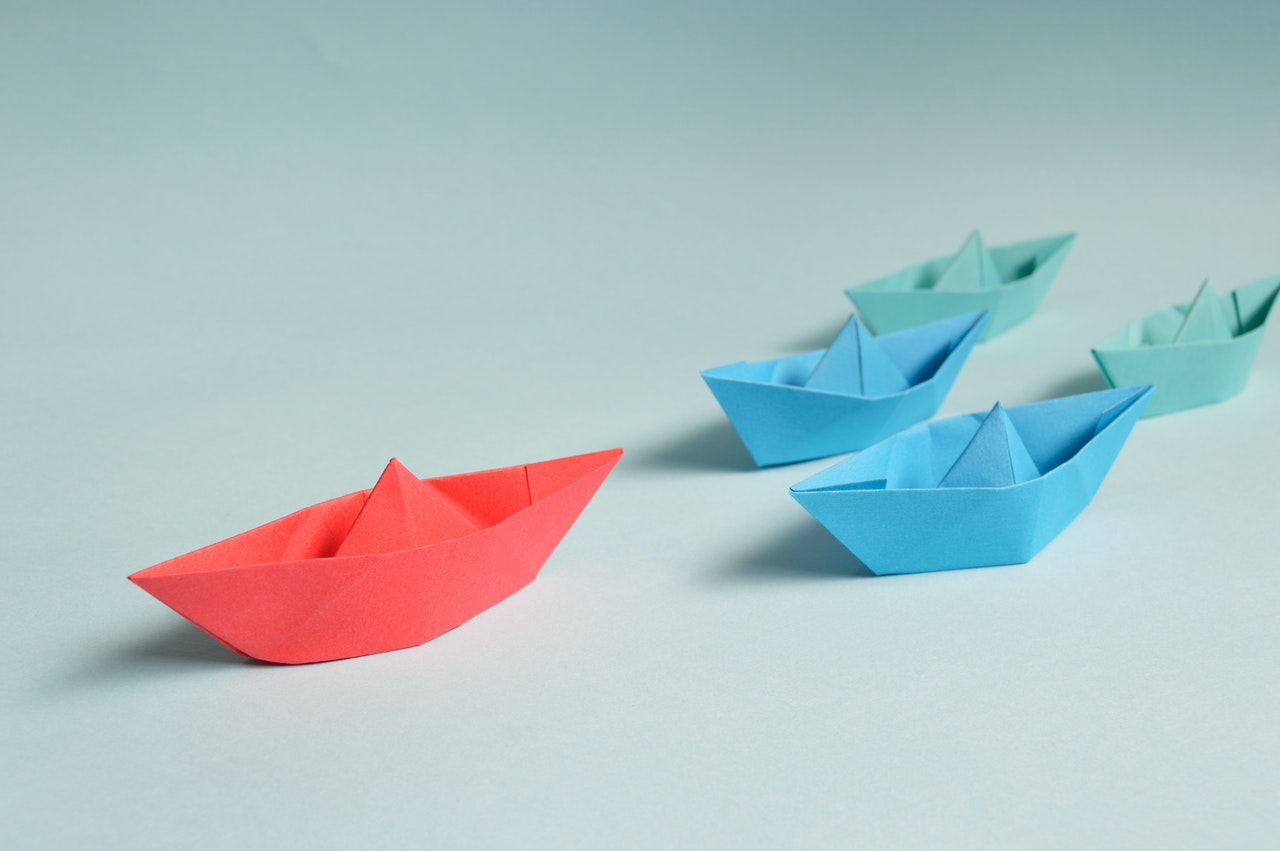 A red paper boat leading the other paper boats