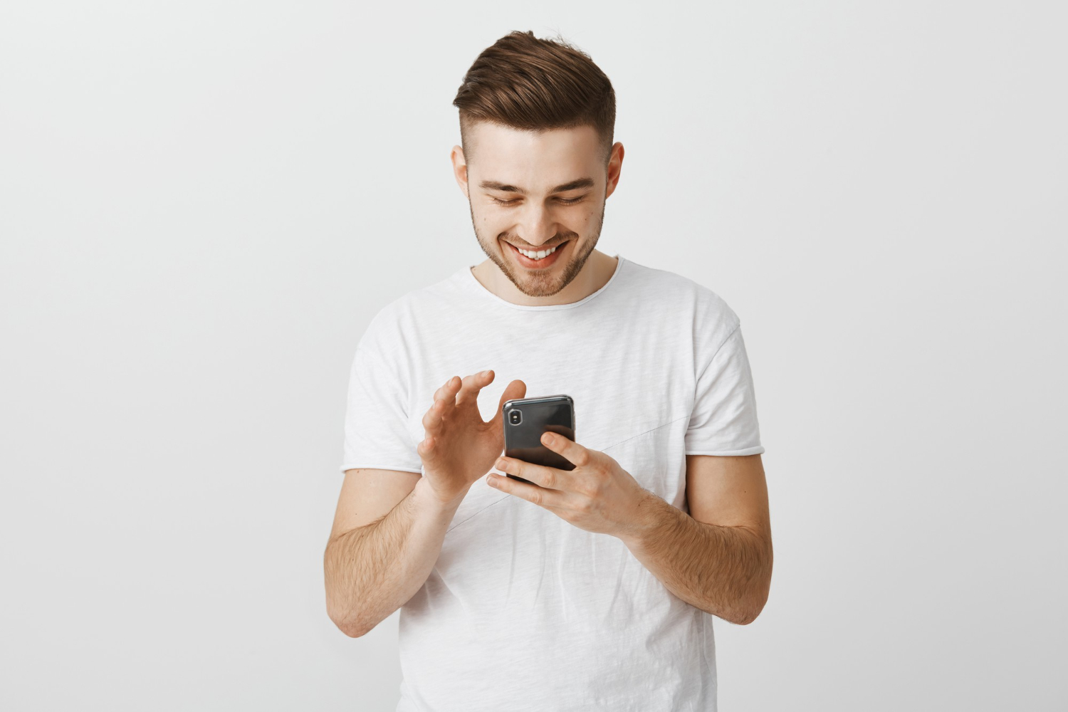 Young man using phone while smiling
