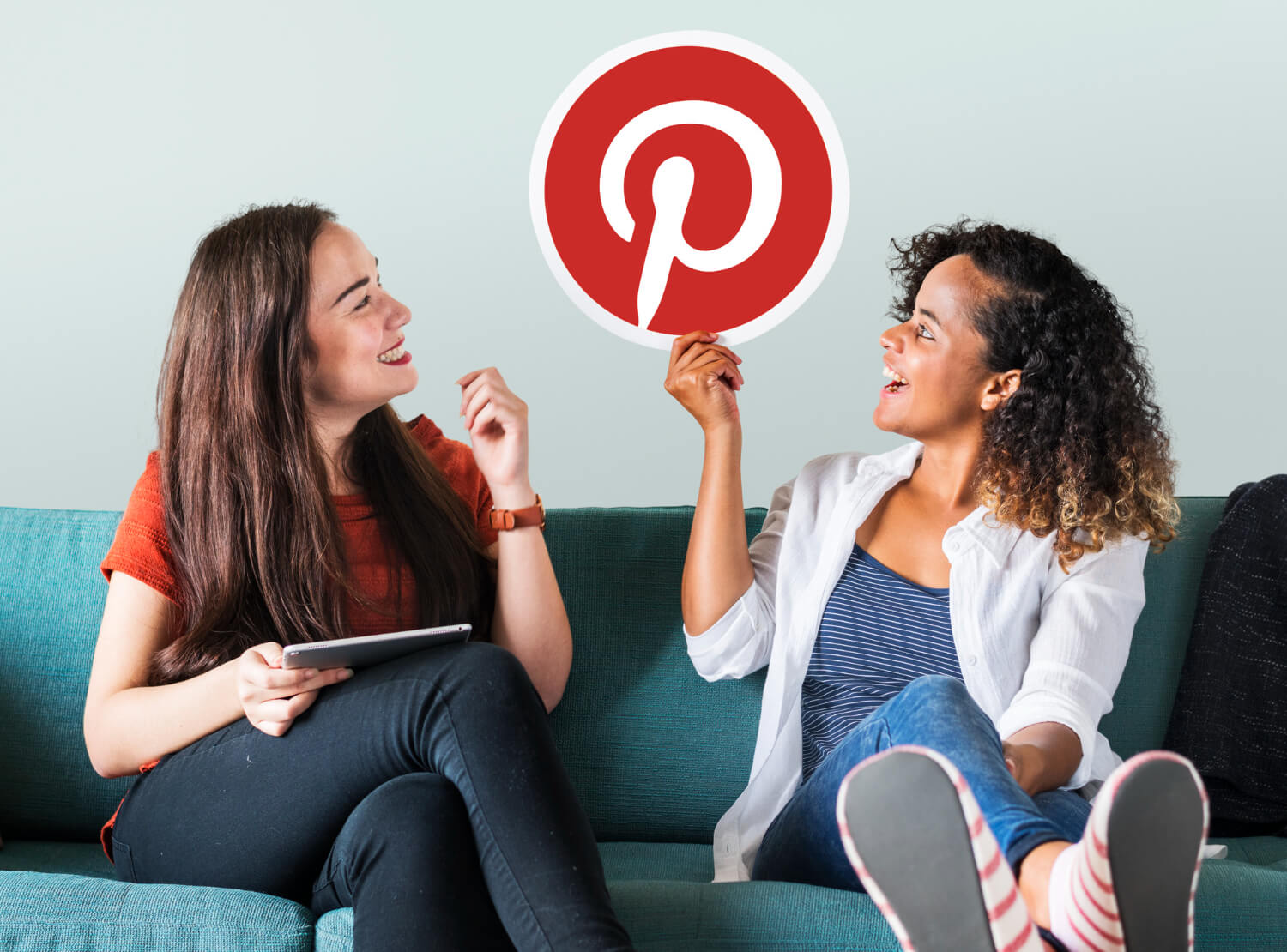 Young women smiling while showing pinterest icon