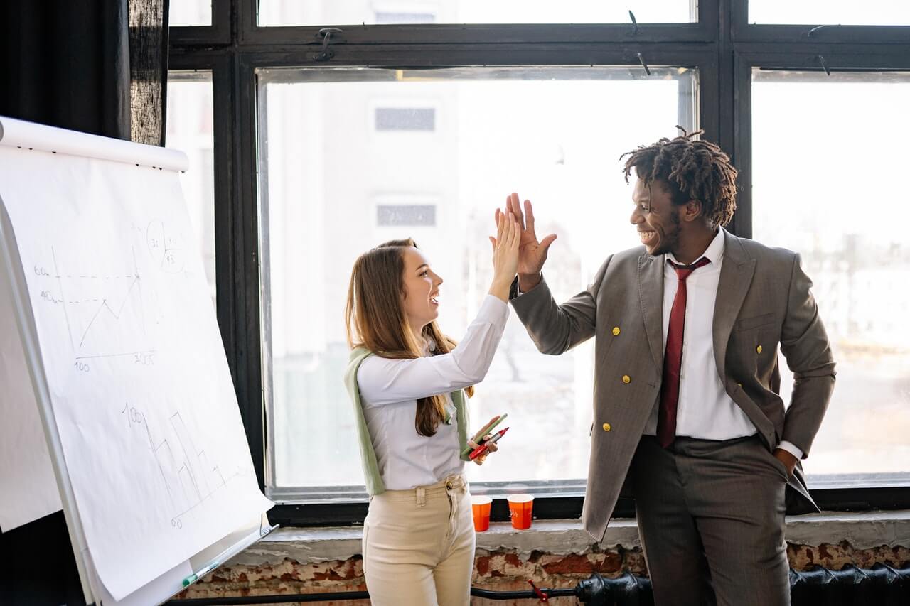 Business man and woman having an high five after a presentation