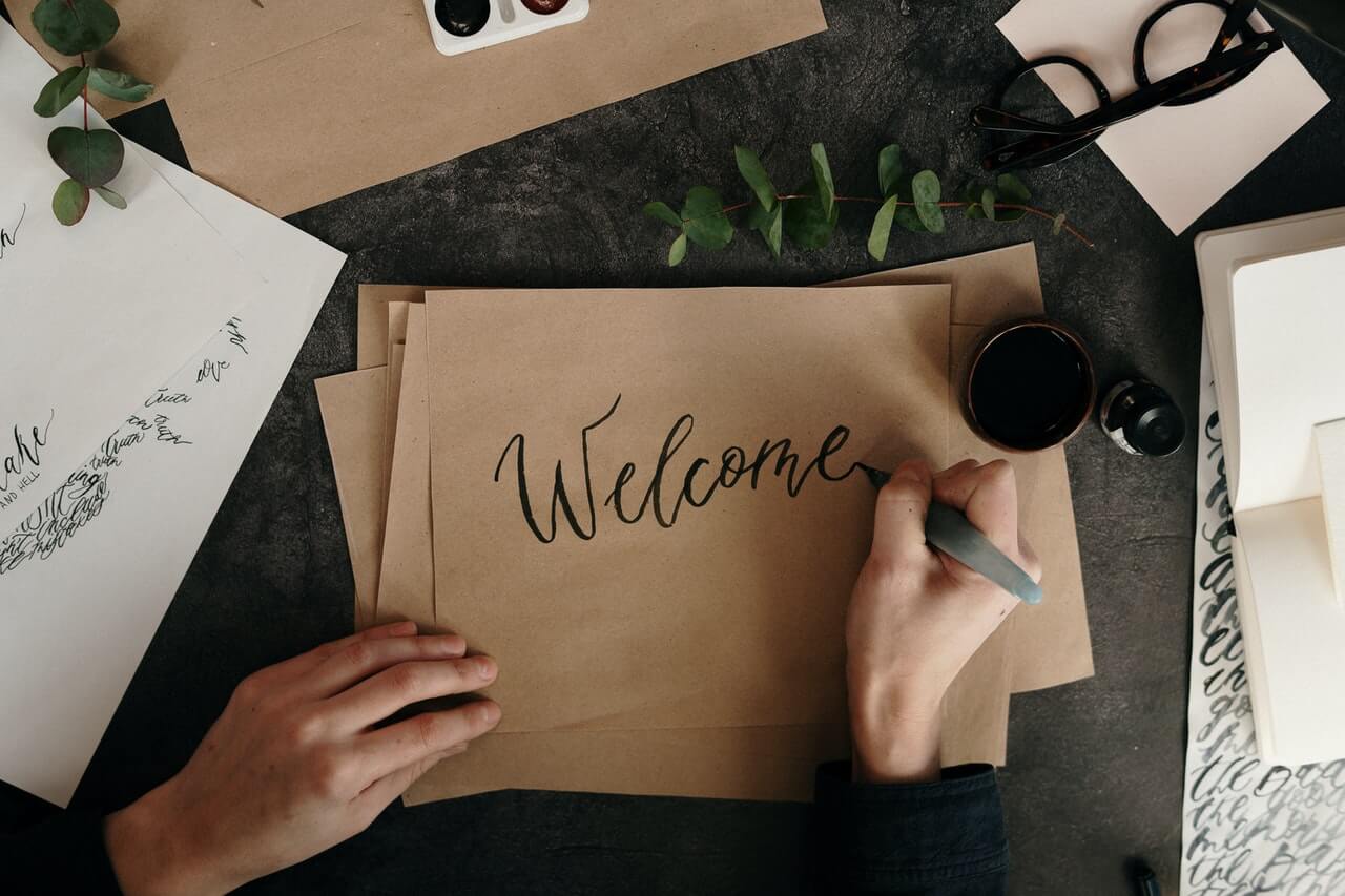 Person writing welcome on a brown paper