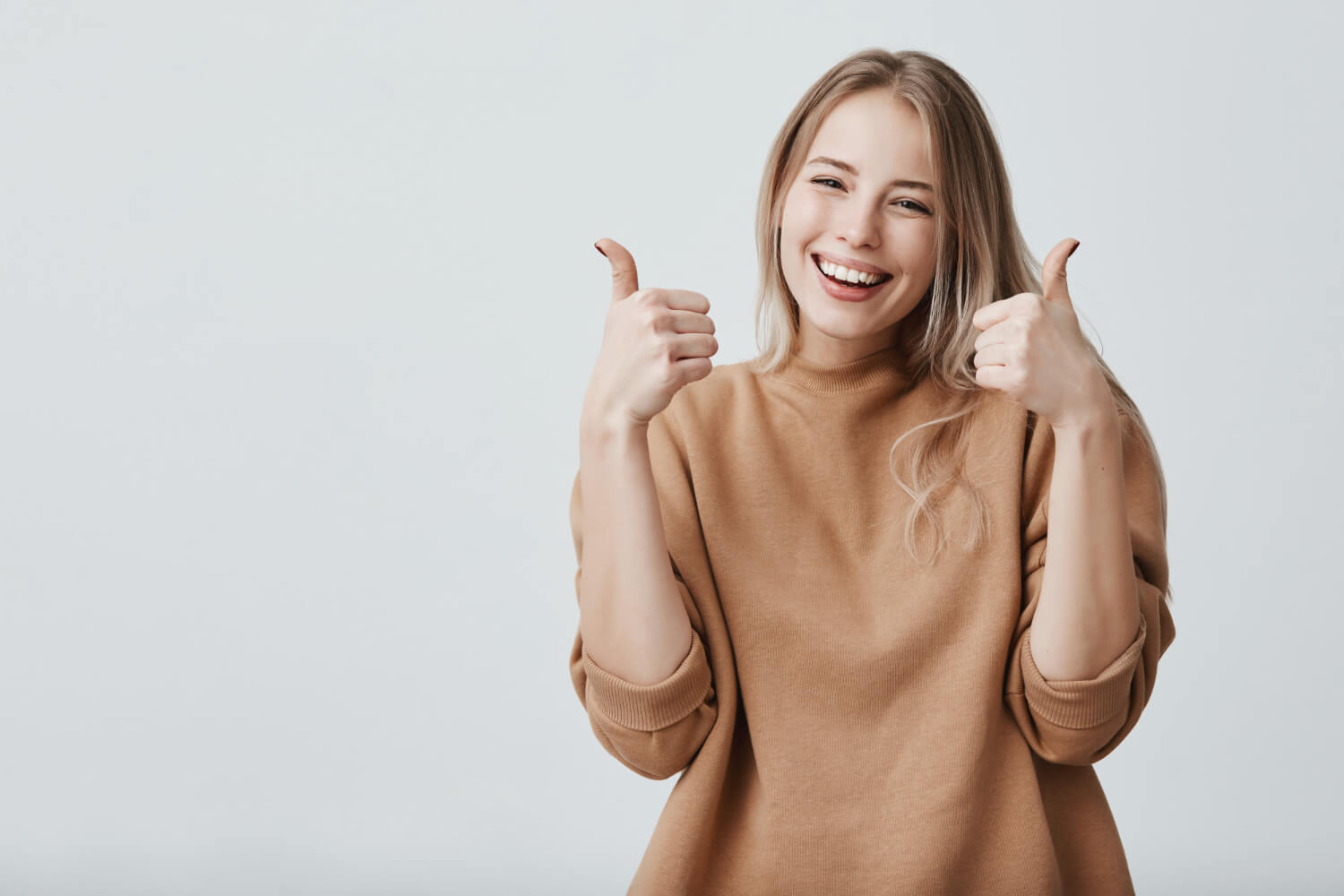 Young woman with broad smile thumbs up