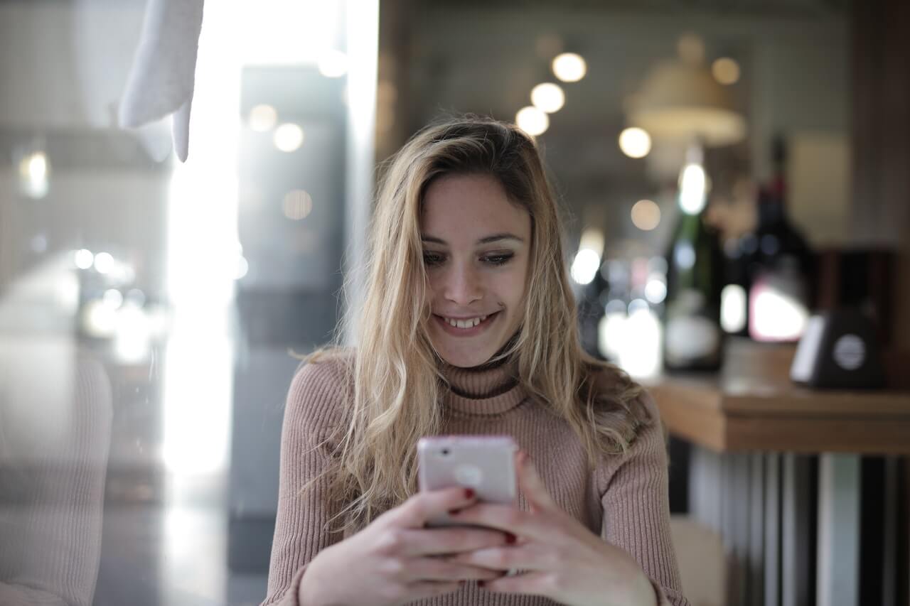 Young lady smiling down on her phone while chatting