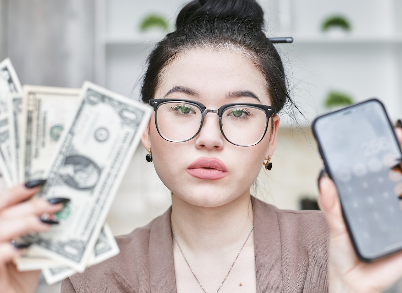 A Woman Holding a Phone and Cash