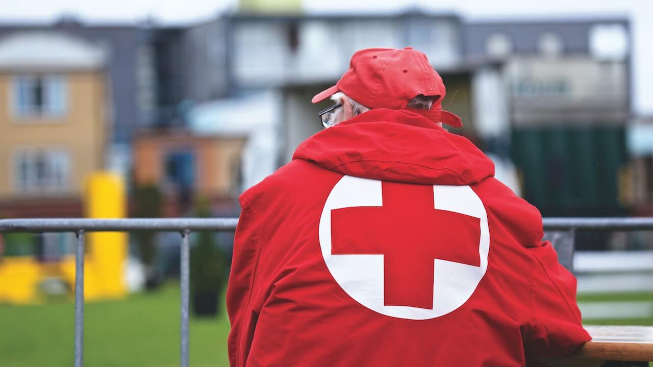 A-red-cross-worker-sitting-and-backing-the-camera.