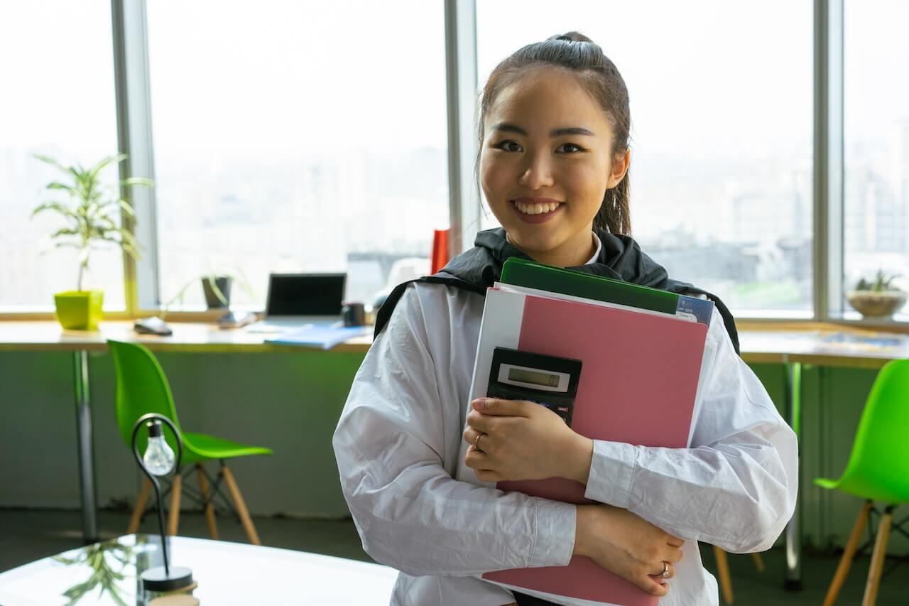 A-young-woman-holding-documents-with-calculator-and-smiling.