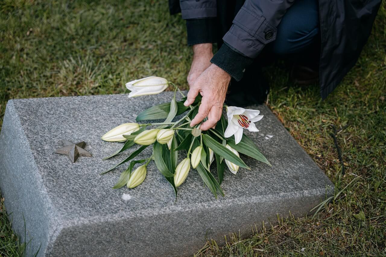 Someone dropping flowers on a tombstone