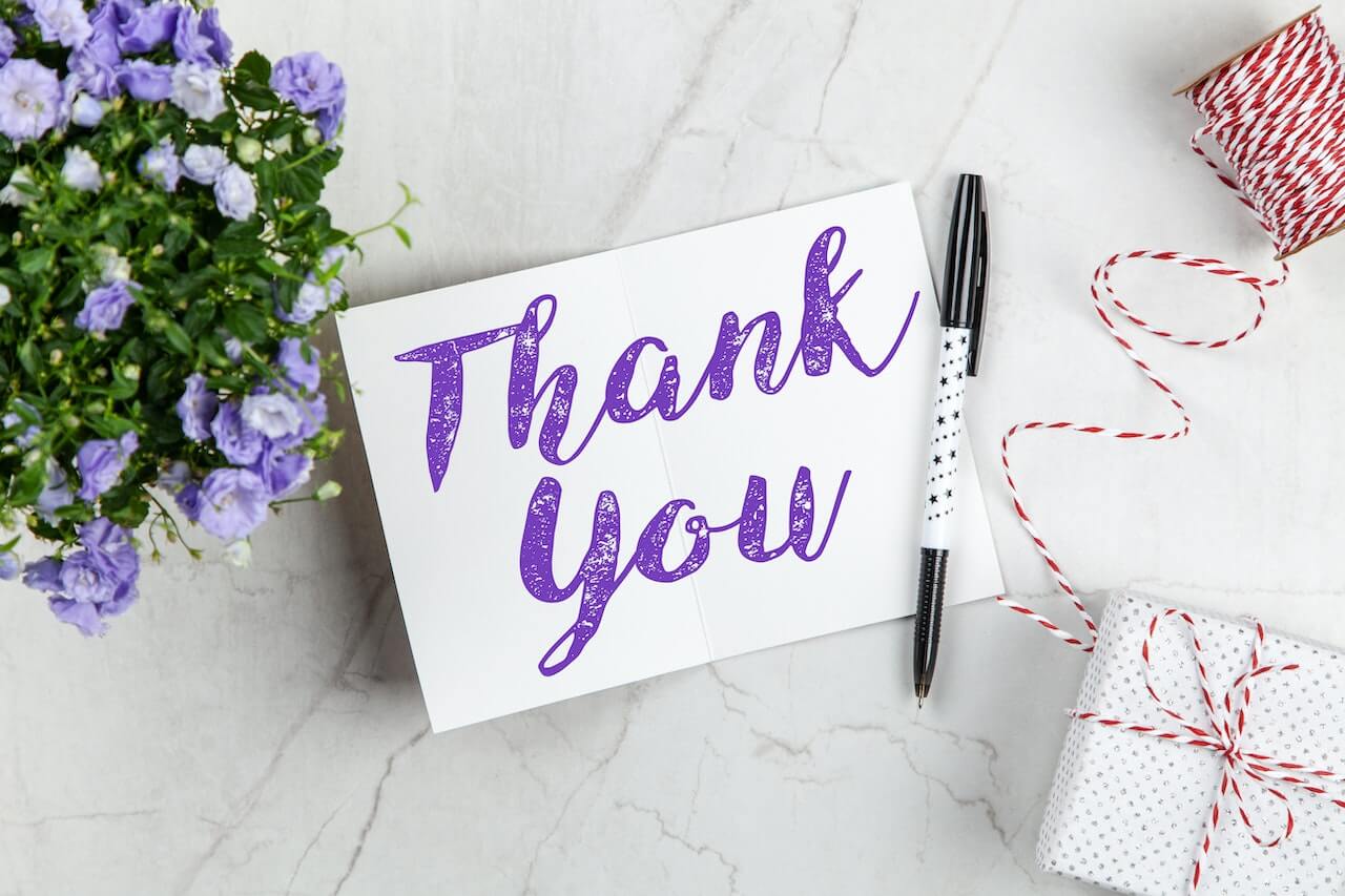 A thank you card on a table with a gift box