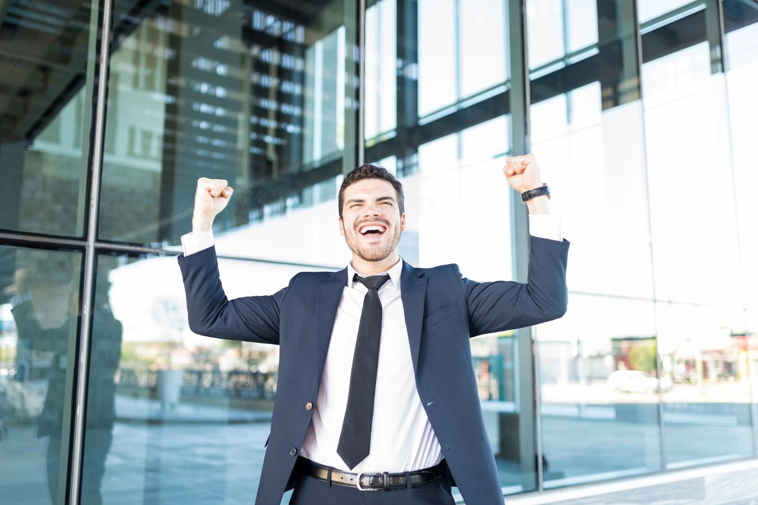 cheerful-hispanic-businessman-raising-arms-celebrating-victory-outside-office-building.