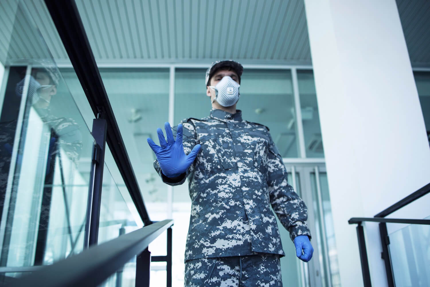soldier-military-uniform-with-rubber-gloves-face-protection-mask-guarding-hospital-gesturing-stop-sign