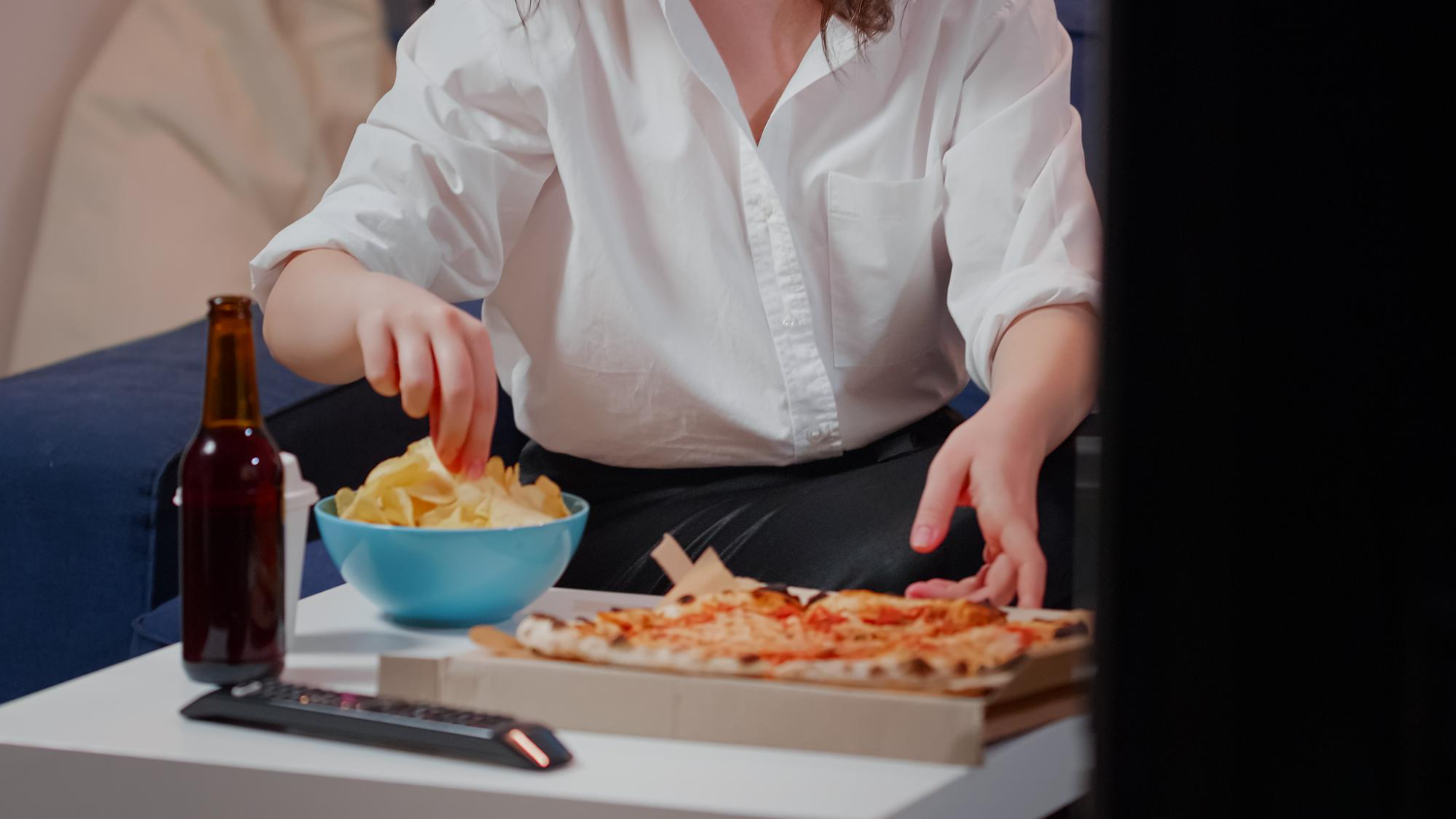 woman-placing-box-pizza-table-while-having-beverages-bowl-chips.