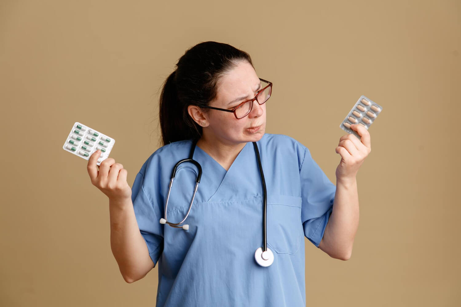Female -nurse-holding-pills-looking-confused-trying-make-choice-
