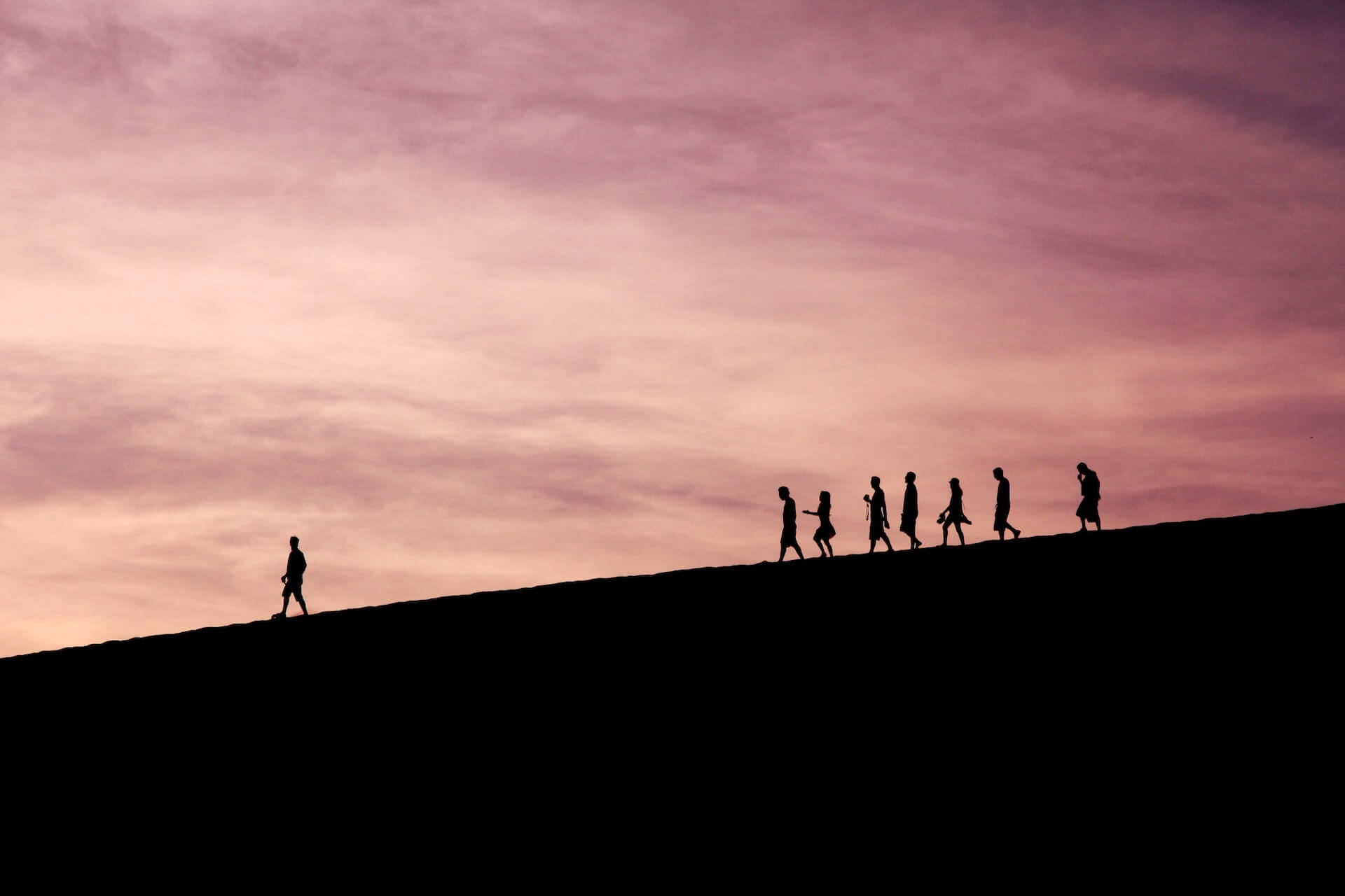 Silhouette of people following their leader on a hill