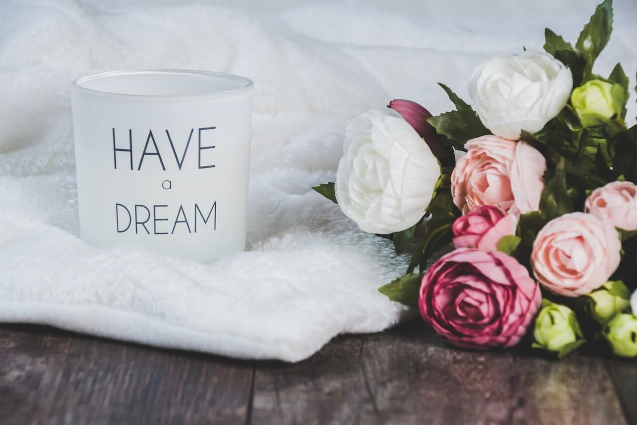 White mug on a wooden desk with the inscription "have a dream"