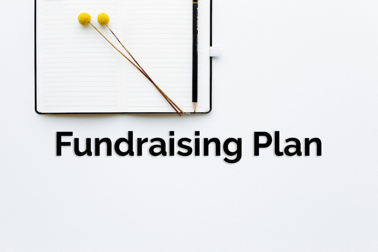 Fundraising plan text on a white background close to an opened book