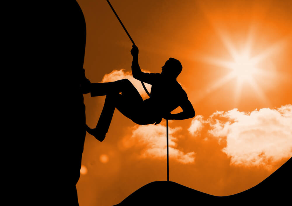 Man climbing a mountain with a rope