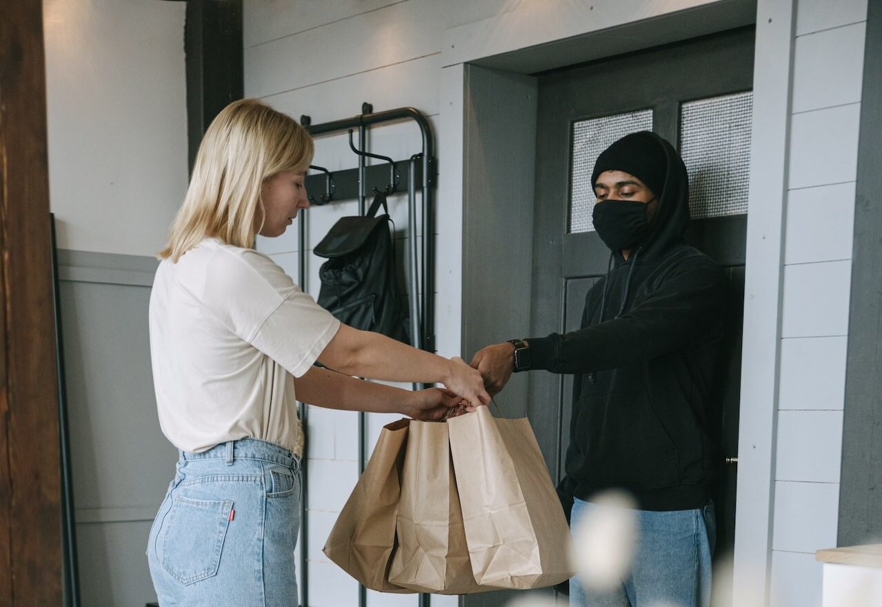 Man giving a brown paper bag to a lady