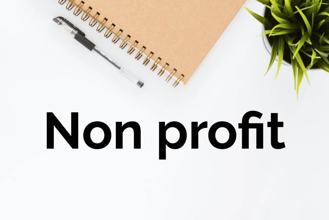 Non profit written on a white background close to a note