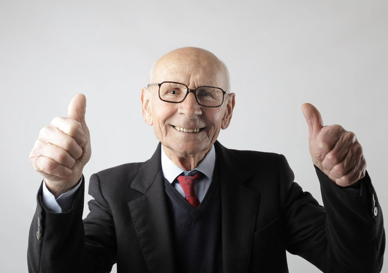 Positive senior man in eyeglasses showing thumbs up