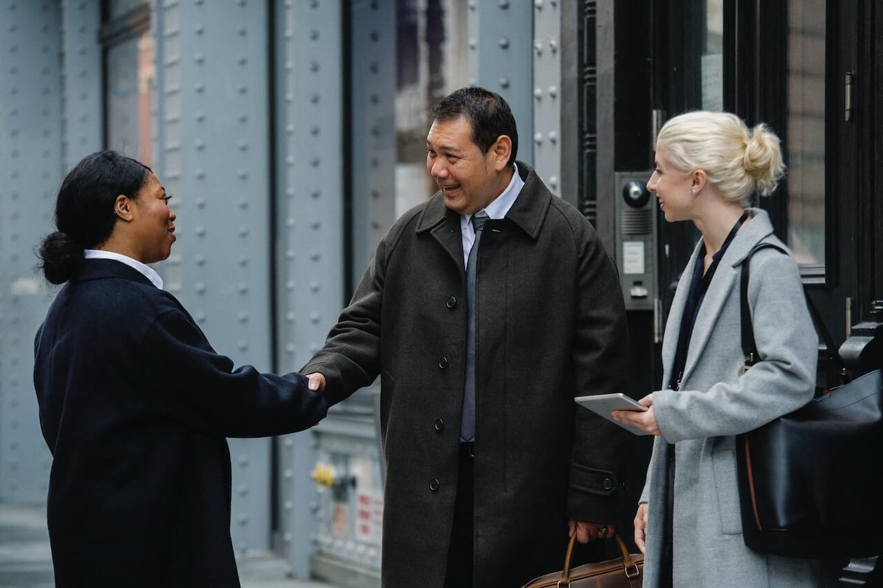 Smiling business partners shaking hands on street before meeting