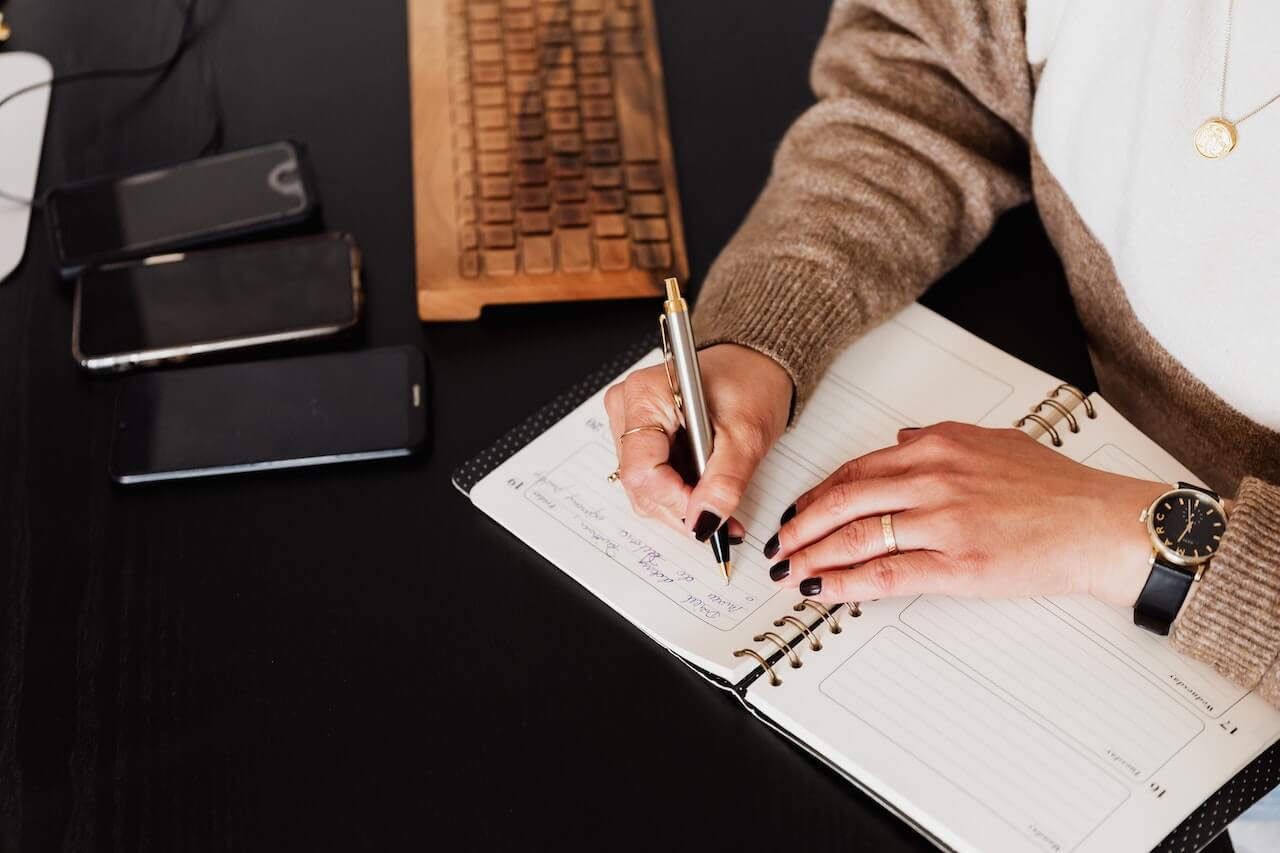 Stylish woman writing in notebook on the desk