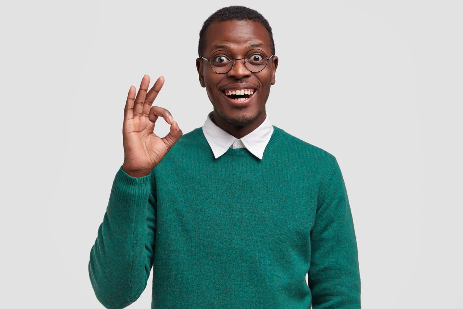 Young smiling man shows okay hand gesture