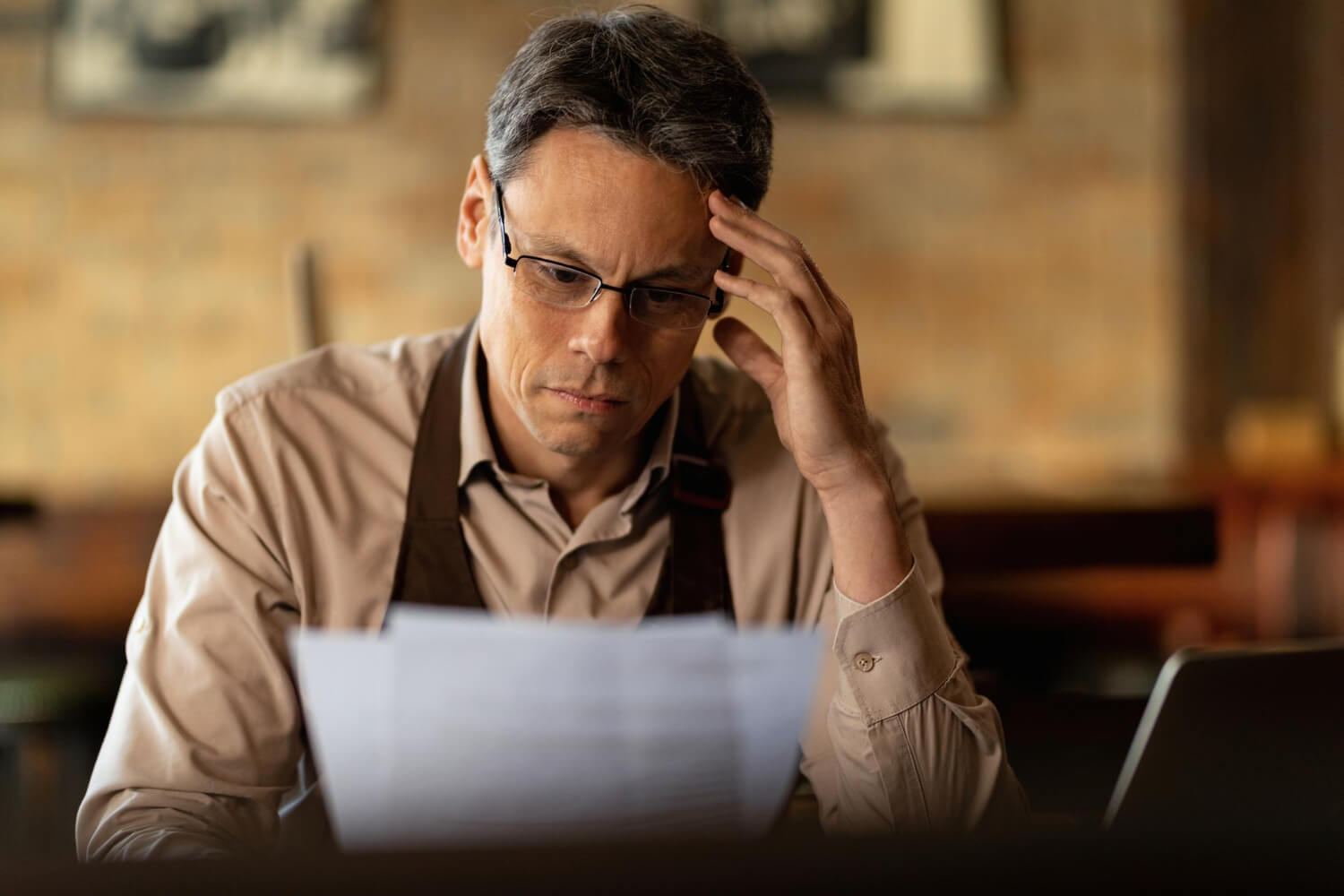 distraught-small-business-owner-reading-reports-while-going-through-paperwork