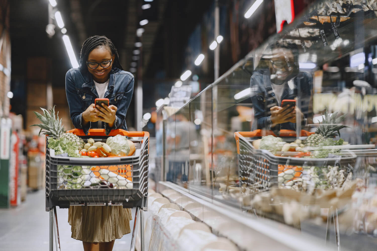 woman-shopping-vegetables-in-a-supermarket-and-pressing-her-phone.