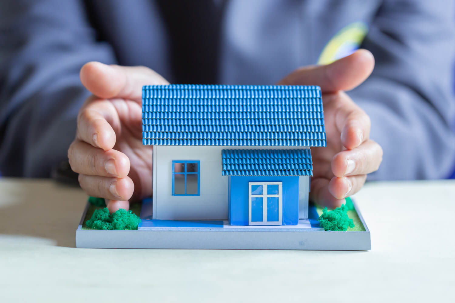 hands holding a blue house model