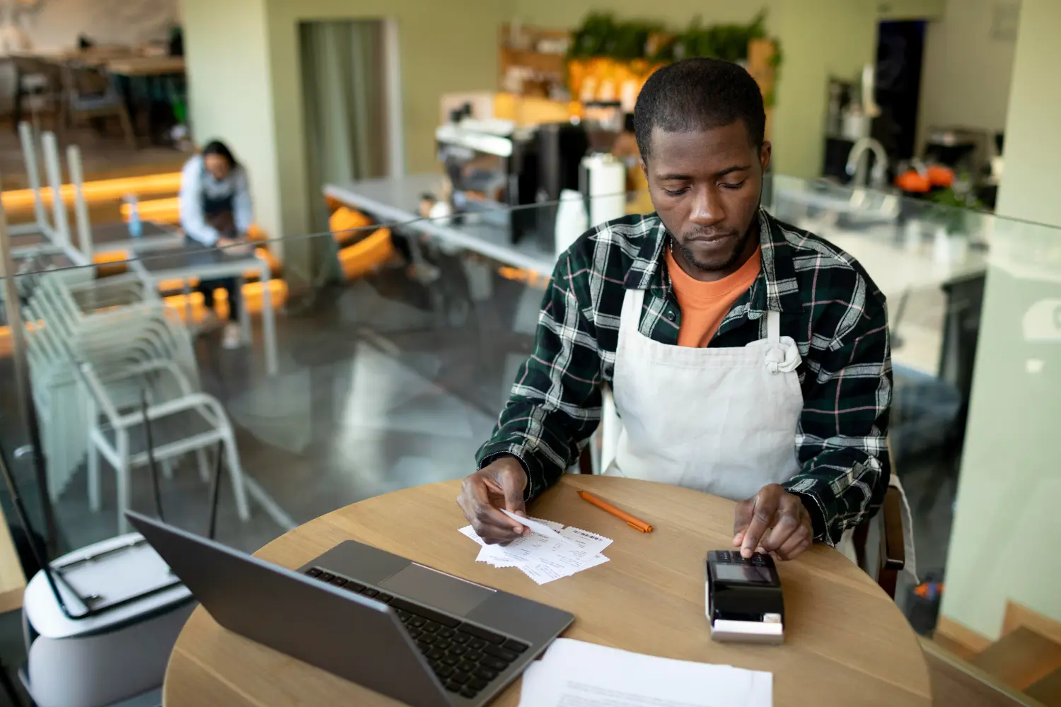 Small business owner in his shop checking receipts with a POS machine