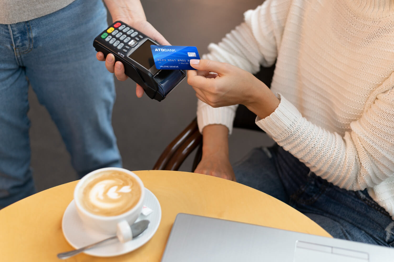 Person paying for their coffee with their ATM card on a small business' POS machine