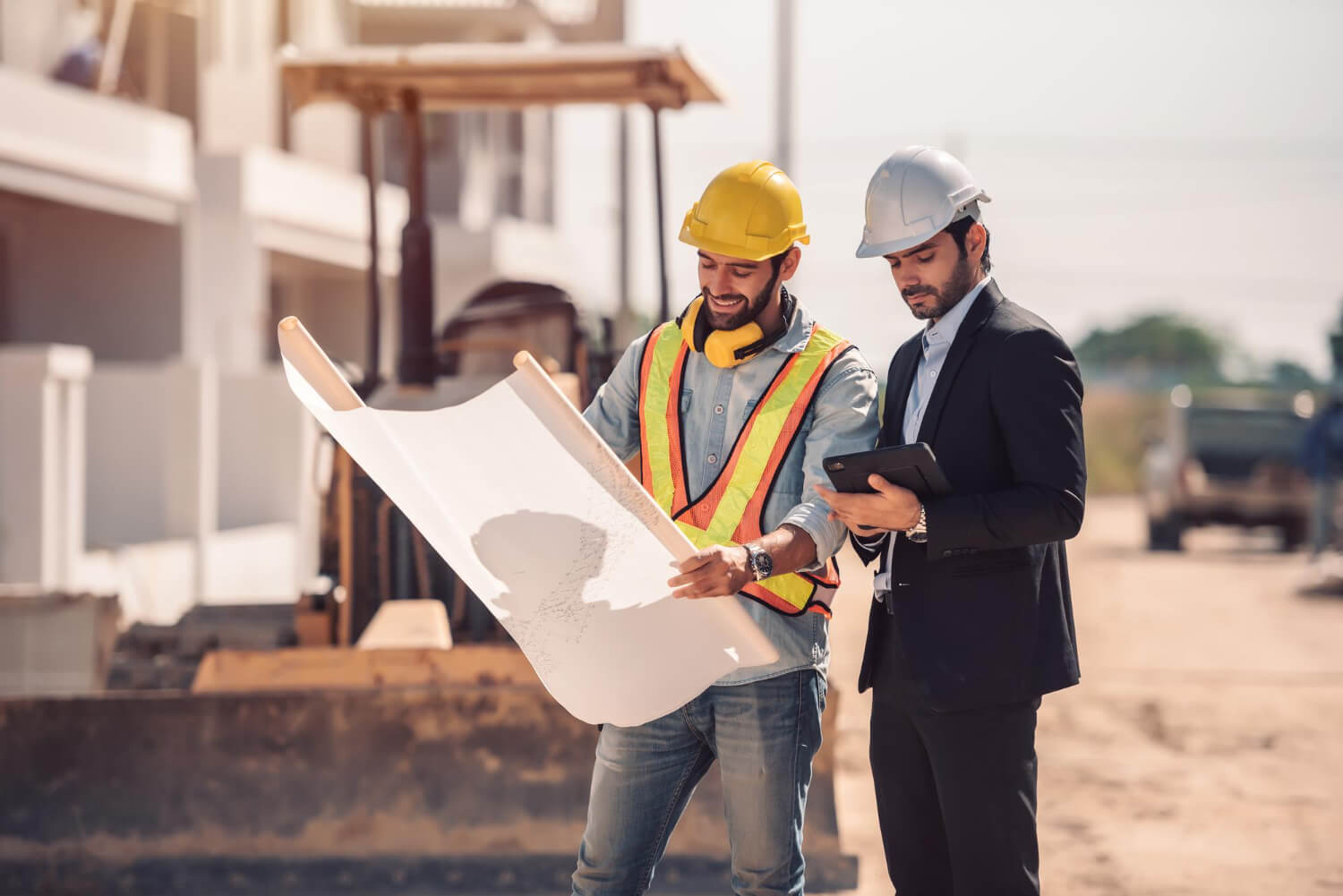 civil engineer and construction worker manager holding digital tablet and blueprints at a construction site