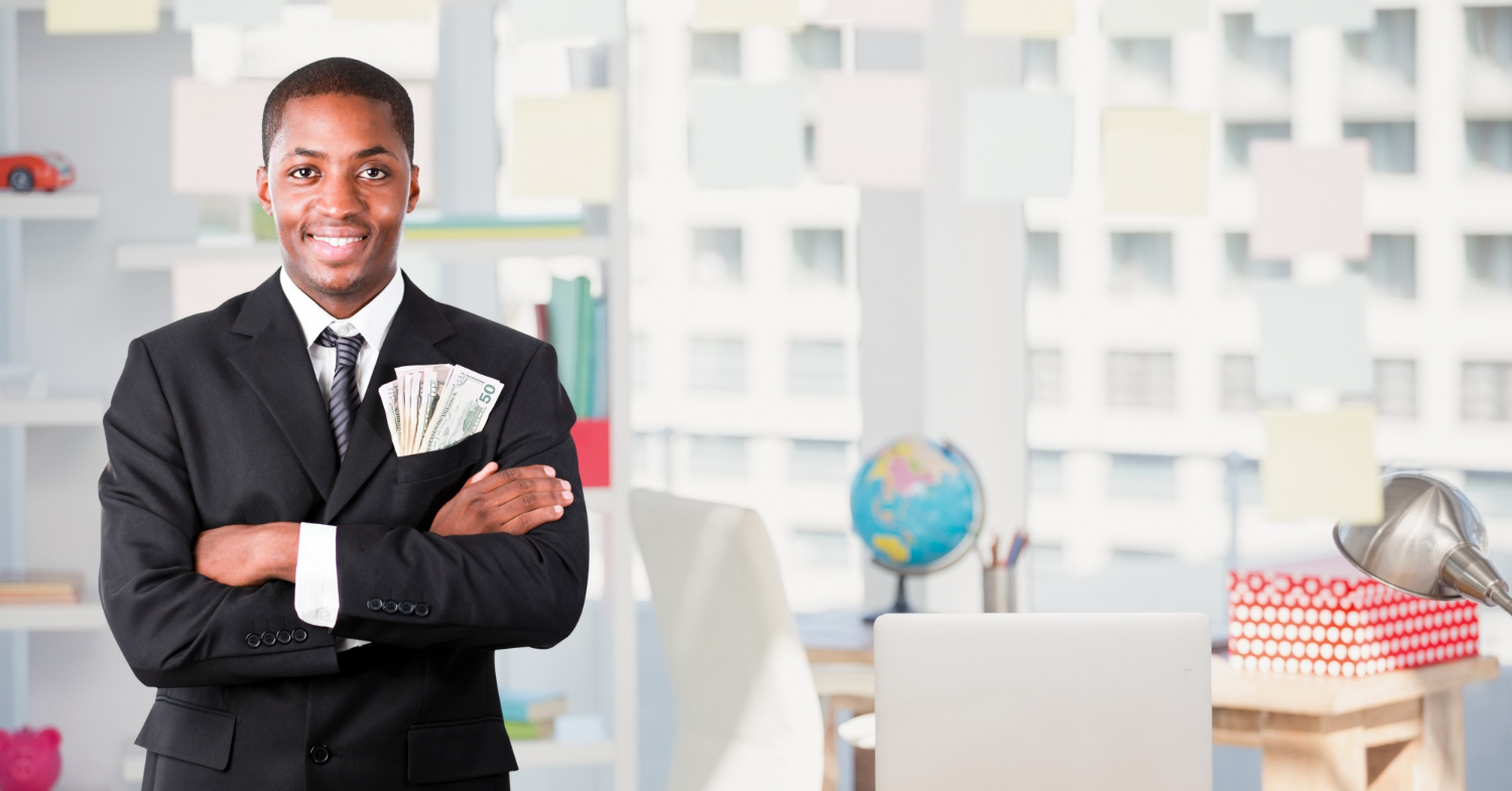 Businessman standing in the office with dollar bills peeping out of his breast pocket